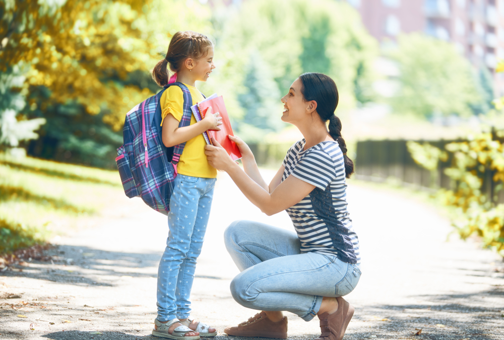 mother and daughter talking on sidewalk with backpack