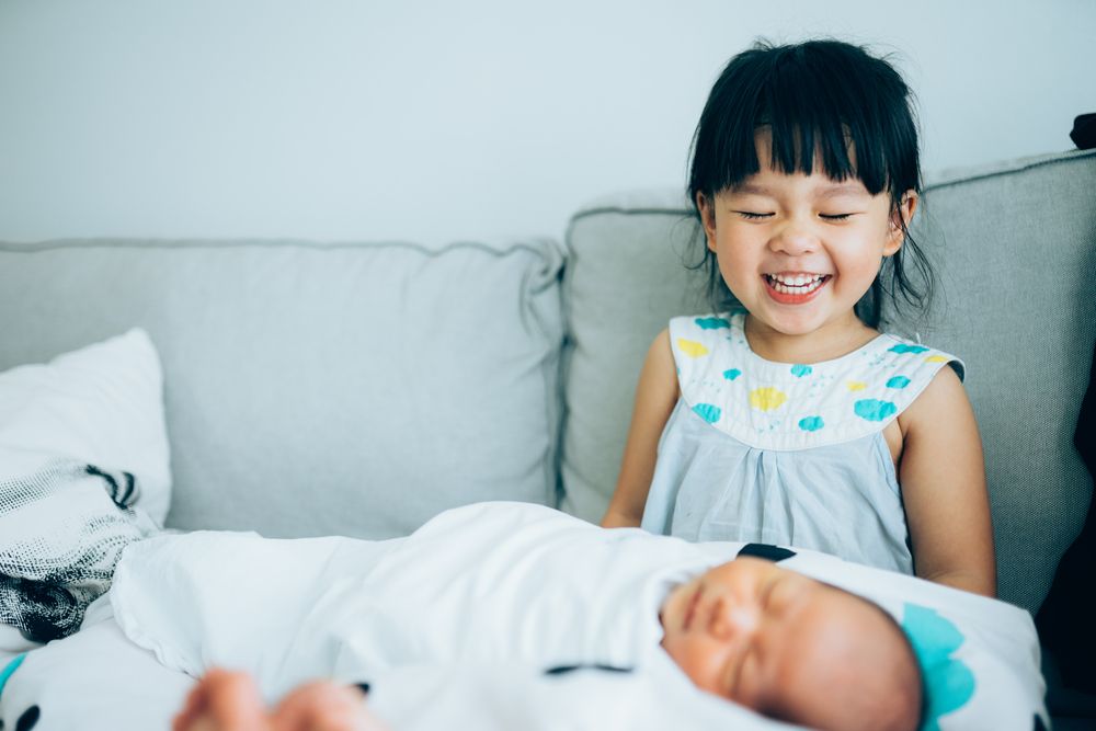 Little sister hugging her newborn brother.