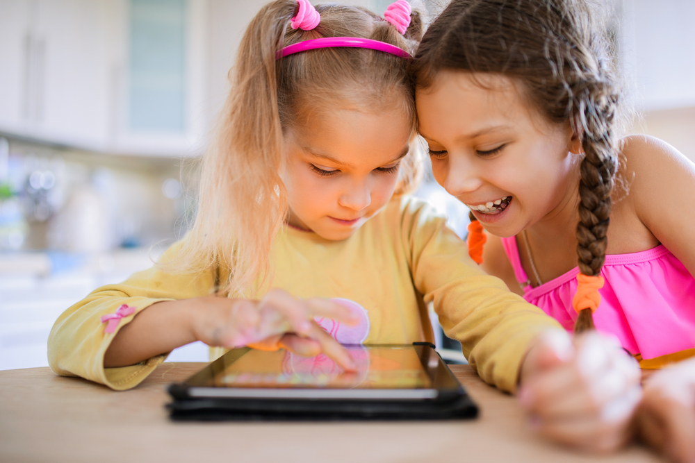 two little girls playing on a tablet