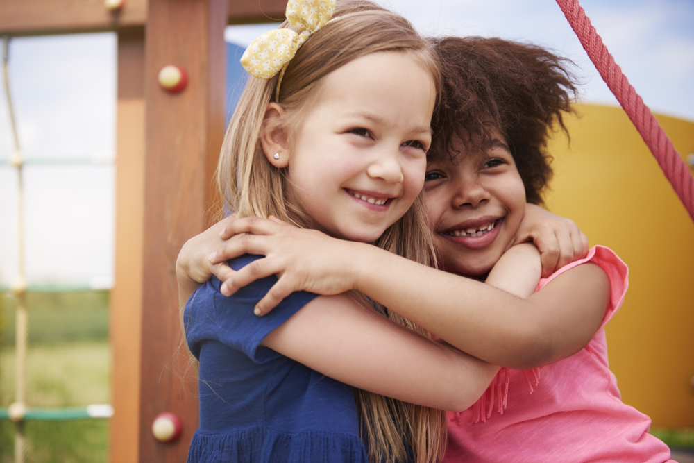Two girls hugging on playground.