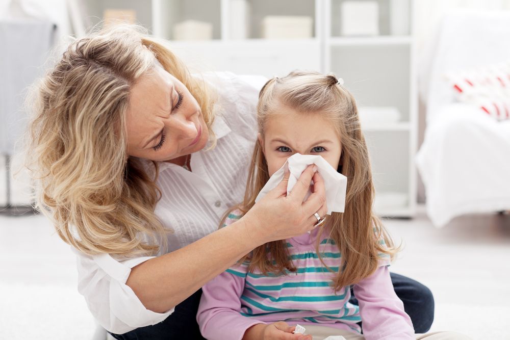 mom blowing childs nose.